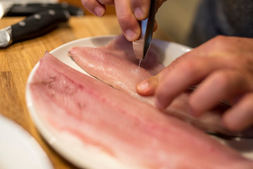 Fischgräten mit Zange aus Filet ziehen, Nahaufnahme mit zwei Gräten und Händen eines Mannes