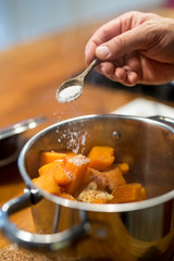 gekochte Süsskartoffel Würfel in Topf, salzen, Hand, Holzlöffel, Butterwürfel, Nahaufnahme