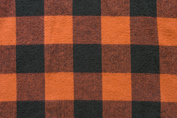 Fabric with black and orange cages pattern. Plaid material. Clothes background