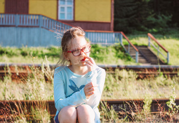 Portrait of charming smiling girl in glasses on background of railway, summer time in country side