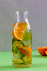 Squeezed orange and lime in a glass bottle with mint and sugar, bright colours and healthy lifestyle trend. Space for text.