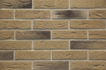 light brown stone brick exterior wall in hard light emphasizing stone's textures and depth
