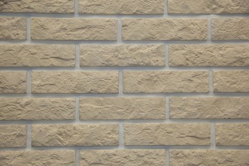 light brown stone brick exterior wall in hard light emphasizing stone's textures and depth