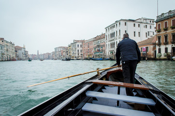Fototapeta na wymiar Un gondoliere rema per far attraversare con il traghetto gondola il Canal Grande di Venezia ai cittadini