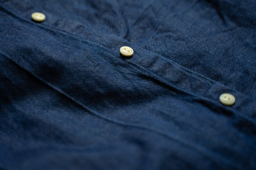 Blue denim shirt with white buttons close-up. Garment background
