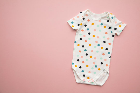 Cute Polka Dot Baby Body Suit Layout On A Pastel Pink Background