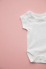 Cute baby white body suit layout on a pastel pink background