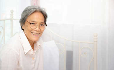 Fototapeta premium Asian women, two-color skin Wearing short hair glasses sitting in the room and she is smiling.In the bedroom there are older women too.
