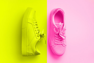 Woman fashion pink shoes on trendy neon pink and yellow colors background with copy space. Top view. Flat lay. Fitness, sport concept. Nude female sneakers