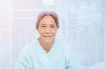 Asian women, two-color skin Wearing short hair glasses sitting in the room and she is smiling.In the bedroom there are older women too.
