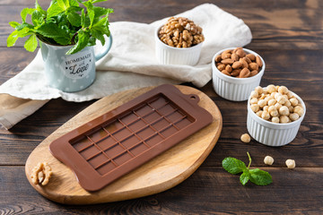 Mold for chocolate bar with different nuts on the table. Chocolate making, chocolatier