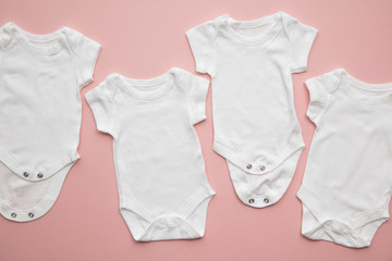 Cute baby white body suit layout on a pastel pink background