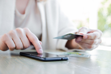 Fototapeta premium A woman in a white jacket, paying by credit card online, making orders over the Internet. Successful woman businessman making a transaction using mobile banking application. Selective focus