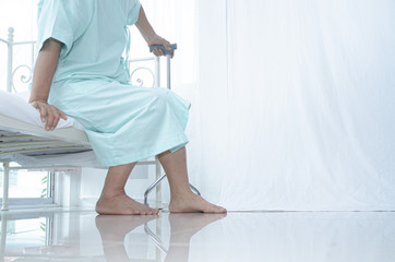 Asian elderly Wearing a green shirt Got out of bed in the nursing room.Elderly women caught the wood to help walk.