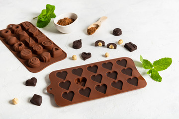 Handmade chocolate candies in molds on white background. Side view