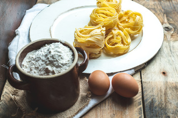 traditional Italian cuisine, raw tagliatelle on the kitchen table surrounded by flour and eggs