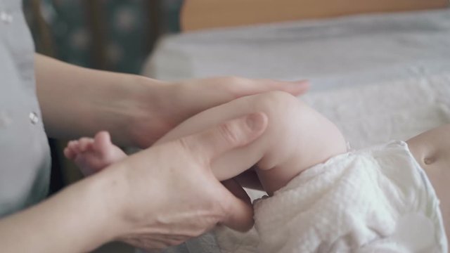 skilled pediatrician holds little infant boy leg and practice hypertonus massage professionally close view