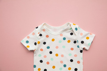 Cute polka dot baby body suit layout on a pastel pink background