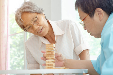Asian elderly women Wearing a blue shirt And friend are playing games Have fun in the morning at home in the room.