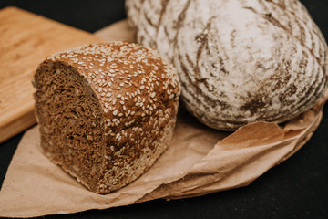 Fresh bread on paper on wooden black background