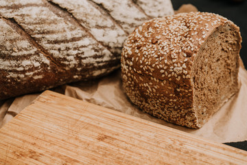 Fresh bread on paper on wooden black background