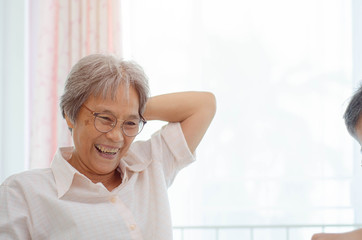 Asian elderly women Wearing a blue shirt And friend are playing games Have fun in the morning at home in the room.