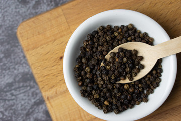 Black pepper in a bowl on dark background.