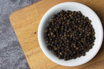 Black pepper in a bowl on dark background.