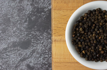 Black pepper in a bowl on dark background.
