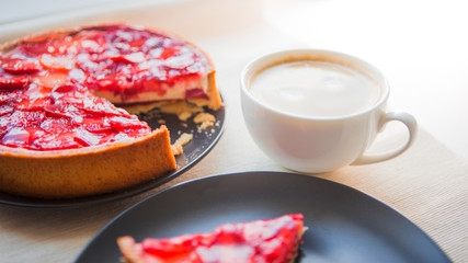 Still life with a Cup of coffee and sweet dessert with strawberries, cheesecake cake with slices of berries in jelly on top.