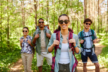 travel, tourism, hike and people concept - group of friends with backpacks in forest