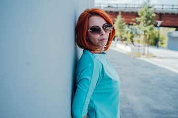 Portrait of young red-haired woman in casual clothes and with sunglasses.