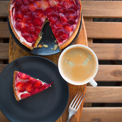 Still life with a Cup of coffee and sweet dessert with strawberries on a wooden table, cheesecake cake with slices of berries in jelly on top.