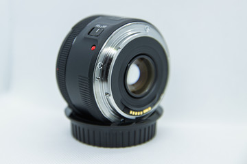 Macro close-up photo of lens to DSLR camera on white background lens captured standing on the cover of the rear element.