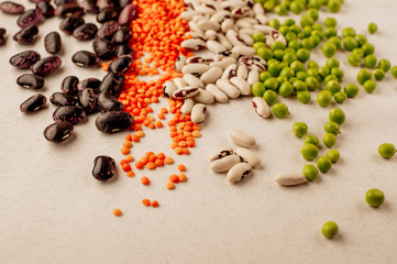 Collection set of various dried legumes laid out in a horizontal line, chaotic order: red lentils,green peas, red beans, white beans close-up on a white background. Selective focus