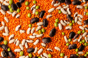Collection set of various dried legumes laid out as a background for an inscription, chaotic order: green peas, red beans, white beans close-up on a white background. Selective focus