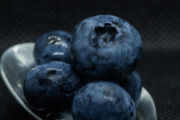 Blueberries Macro closeup photo of superimposed on top of each other and tiled in a teaspoon against a dark background.