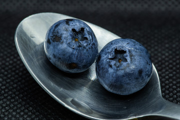Blueberries Macro closeup photo of superimposed on top of each other and tiled in a teaspoon against a dark background.