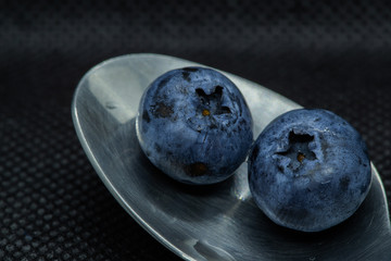 Blueberries Macro closeup photo of superimposed on top of each other and tiled in a teaspoon against a dark background.