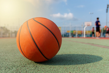 Basketball ball on court on a sunny day. Green polypropylene court outdoors