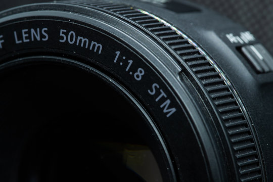 Macro close-up photo of lens to DSLR camera on dark background front view with focal range and aputure description.