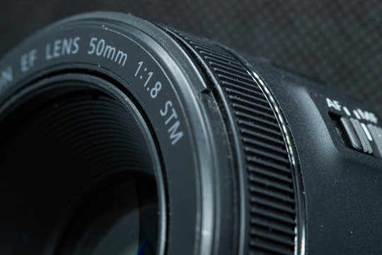 Macro close-up photo of lens to DSLR camera on dark background front view with focal range and aputure description.