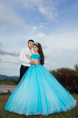 Fototapeta premium The guy and the girl on nature. A pair of lovers embrace against the backdrop of a beautiful river landscape. Concept relationship. Love story of the beautiful young man and woman. 