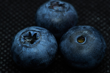 Blueberries Macro close-up photo of laying on a black mat covered with drops of water.