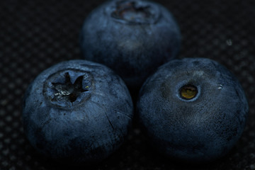 Blueberries Macro close-up photo of laying on a black mat covered with drops of water.