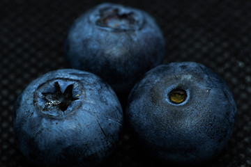 Blueberries Macro close-up photo of laying on a black mat covered with drops of water.