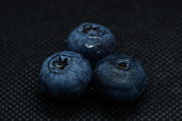 Blueberries Macro close-up photo of laying on a black mat covered with drops of water.