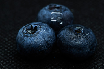 Blueberries Macro close-up photo of laying on a black mat covered with drops of water.