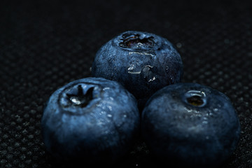 Blueberries Macro close-up photo of laying on a black mat covered with drops of water.