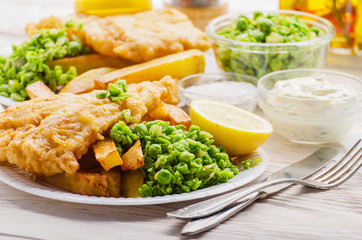 Traditional British street food fish and chips with tartar sauce and mushy peas on paper plate